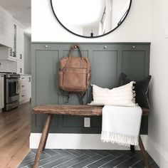 a bench with a purse on it in front of a round mirror above the bench