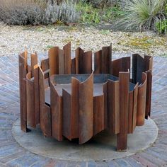 a circular wooden table sitting on top of a brick floor next to a garden area