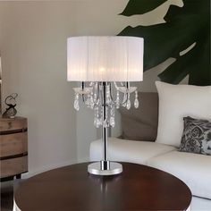 a living room with a white couch and a lamp on the table in front of it