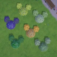 an aerial view of mickey mouse's heads in the grass with flowers and trees around them