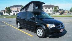 a black van parked in a parking lot with its roof open and it's awning down