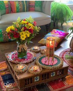 a wooden table topped with lots of colorful plates and flowers next to a vase filled with flowers