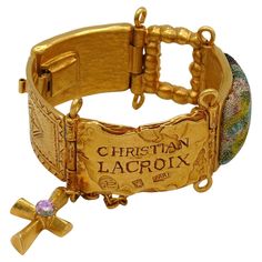 CHRISTIAN LACROIX vintage gold tone bracelet featuring an ID tag link, crystals, links covered with fabrics, chain and cross charm. Marked CHRISTIAN LACROIX CL Made in France. Indicative measurements : length approx. 16.5 cm (6.50 inches) / width approx. 2.3 cm (0.91 inch). Comes with a CHRISTIAN LACROIX dust bag. Material : Gold tone metal hardware / Crystal / Fabric. NOTES - This is a preloved vintage item, therefore it might have imperfections. - Colors may differ slightly from actual product Christian Lacroix Jewelry, Crosses Jewelry, Crystal Fabric, Jewelry Details, Christian Jewelry, Christian Lacroix, Cross Jewelry, Vintage Jewels, Cross Charms