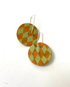 Round spinner disc hoop earrings in line green with orange harlequin/ argyle pattern. The circles dangle loosely allowing them to spin and turn. Bright, fun and very lightweight.  Video shown for shape and movement only.  Length from top of ear wire: 1 and 5/8" Circle diameter: 1 and 1/8"  Polymer clay. Sterling silver ear wires that hook in the back. No more lost earrings!  Handmade, one of a kind (OOAK) Care Instructions provided with purchase www.etsy.com/shop/LindaBrooksDesigns Orange Pierced Metal Earrings, Handmade Orange Circular Earrings, Artisan Orange Round Bead Earrings, Lime Green Clay Earrings, Vintage Orange Round Earrings, Orange Earrings, Earrings Round, Earrings Green, Round Earrings