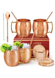 two copper mugs with spoons and ice in them next to a wooden box