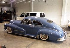 an old blue car parked in a garage