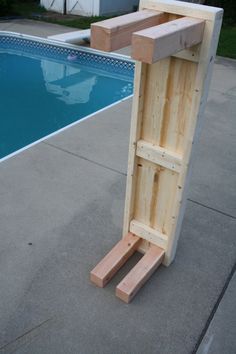 a wooden shelf sitting next to a pool in the middle of a yard with no water