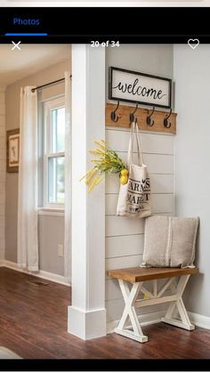 a welcome sign hangs on the wall next to a bench with a plant in it