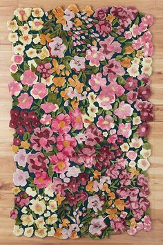 a rug with flowers on it sitting on top of a wooden floor in front of a wall