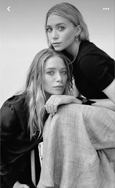 two women sitting next to each other in black and white