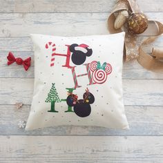 a mickey mouse christmas pillow sitting on top of a wooden floor next to a bow