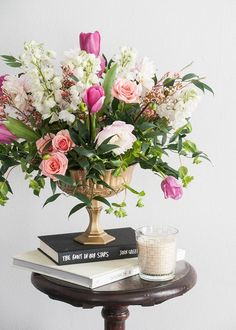 a vase filled with pink and white flowers on top of a table next to a book