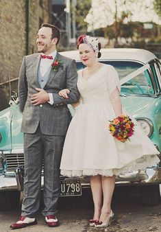 a man and woman standing next to an old car