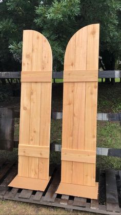 two wooden doors sitting on top of pallets in front of some trees and grass