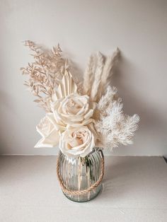 a vase filled with flowers and feathers on top of a white tablecloth covered floor