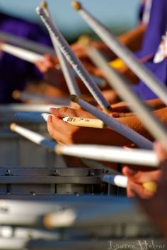 many people are lined up with their hands holding onto some metal rods and pencils