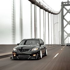 a black car driving down a road next to a bridge