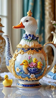 a ducky teapot with two rubber ducks sitting on the table next to it