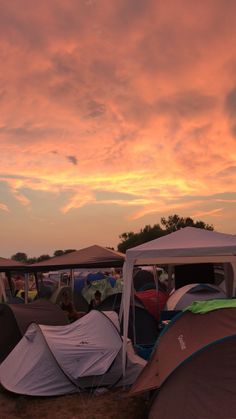 many tents are set up in the field at sunset