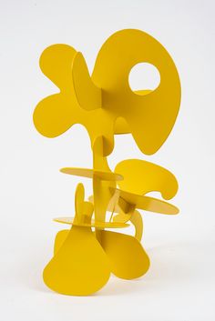 an abstract sculpture made out of yellow paper on a white background with the letter q in the middle