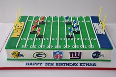 a football field birthday cake is decorated with green bay and rams figurines on it