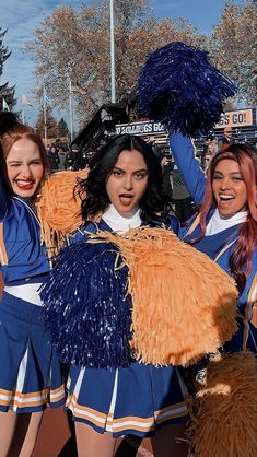 three cheerleaders in blue and orange outfits are posing for the camera with their pom poms