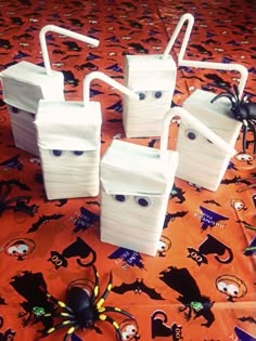 four white plastic boxes sitting on top of a table covered in spider webs and halloween decorations