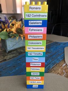 a stack of lego blocks sitting on top of a table next to a vase filled with flowers