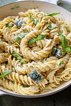 pasta with pesto and parmesan cheese in a skillet on a table