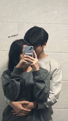 a man and woman taking a selfie in front of a wall with the caption yes i think?