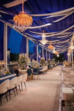 an indoor wedding venue with blue and white linens, chandeliers and tables