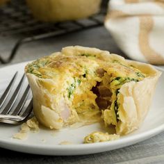 an egg and ham quiche on a white plate with a fork next to it