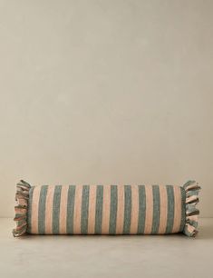 a striped pillow sitting on top of a white floor next to a gray and beige wall