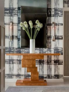 a vase filled with flowers sitting on top of a wooden table next to a mirror