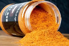 a jar filled with orange colored powder on top of a wooden table