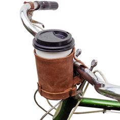 a cup holder attached to the handlebars of a bicycle with a coffee cup in it