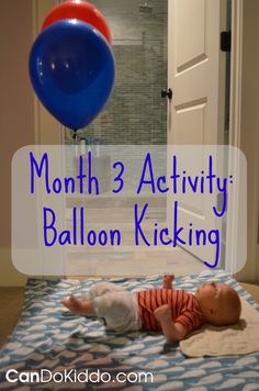 a baby laying on top of a bed next to a red, white and blue balloon