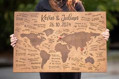 a woman holding up a wooden sign with the names of countries on it and hearts in each country