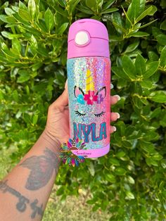 a person holding up a pink and blue water bottle with the word nyyla on it