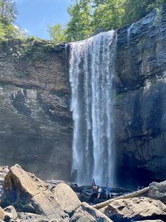 two people standing at the base of a waterfall