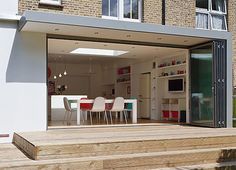 an open living room and dining area on the outside of a house with wooden steps leading up to it