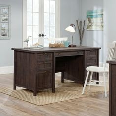 a wooden desk sitting on top of a hard wood floor next to a white chair