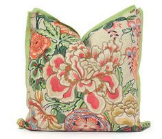 a floral pillow with green trim and pink flowers on the front, sitting on a white surface