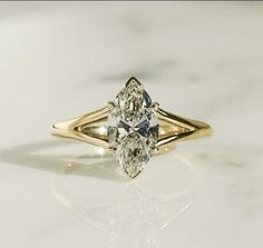 a yellow gold engagement ring with two pear shaped diamonds on the band and an oval cut diamond in the center