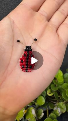 a ladybug beaded necklace on someone's hand with green plants in the background