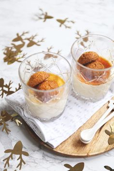 two glasses filled with dessert sitting on top of a wooden tray