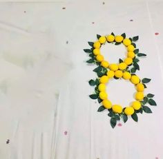 a number made out of lemons and leaves on a white tablecloth with pink flowers