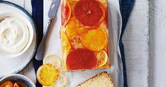 a loaf of bread with orange slices on it next to bowls of yogurt