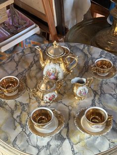 a marble table topped with gold cups and saucers