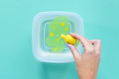 a hand holding a yellow marker in front of a plastic container with green and yellow designs on it